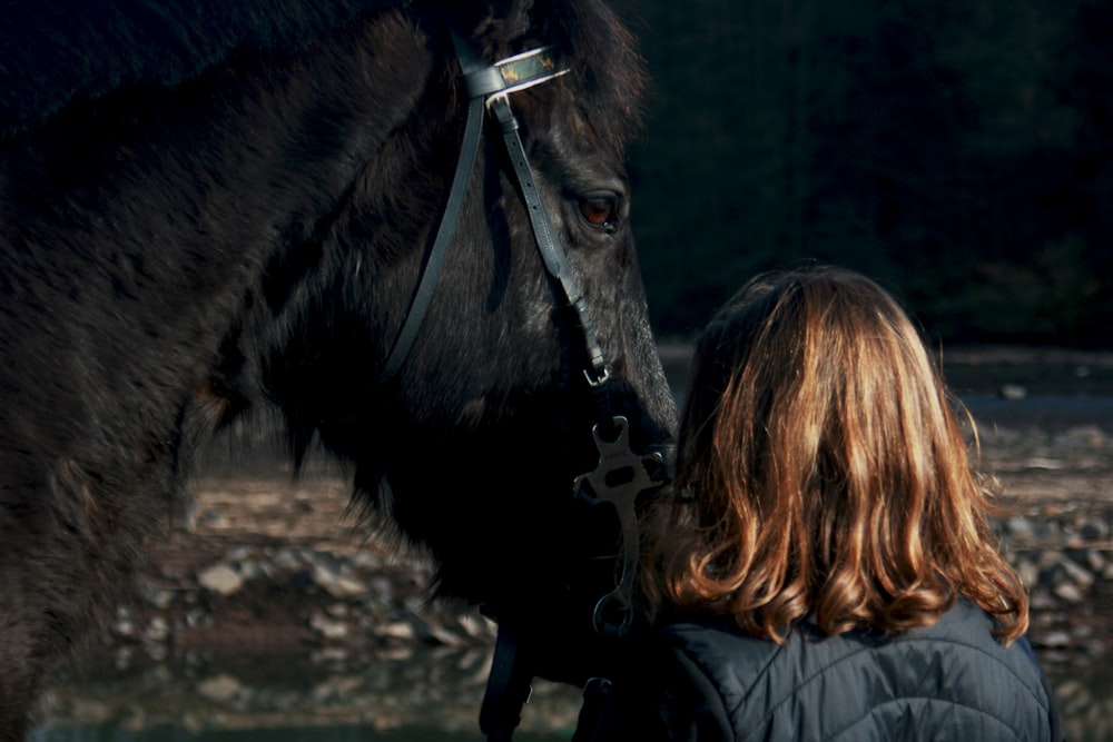 Mujer de pie junto al caballo negro