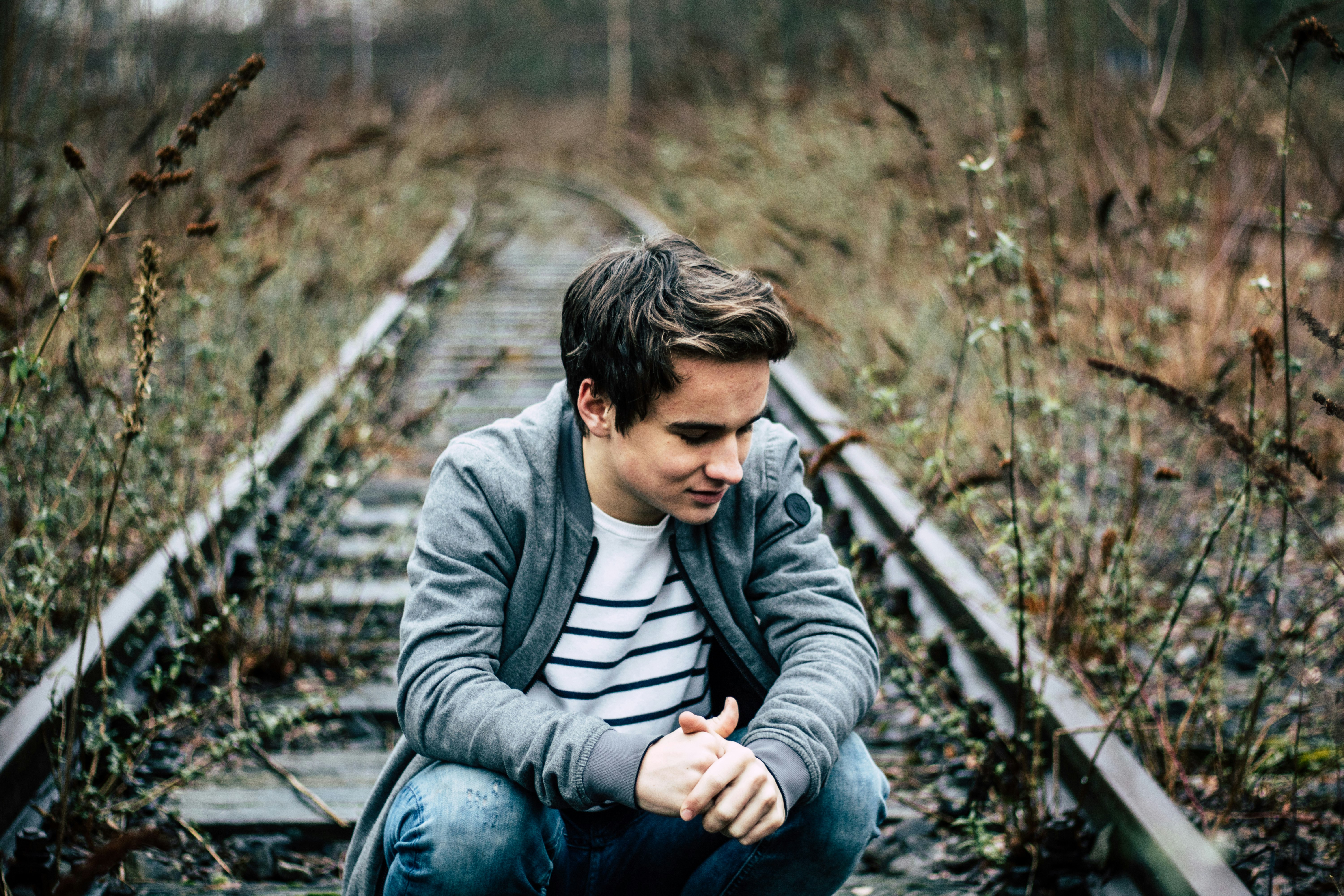 man sitting at the railroad during day