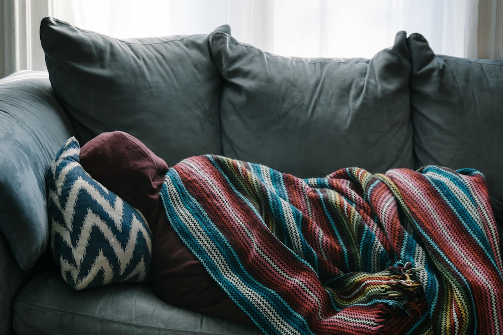 Person liegt auf grauem Sofa