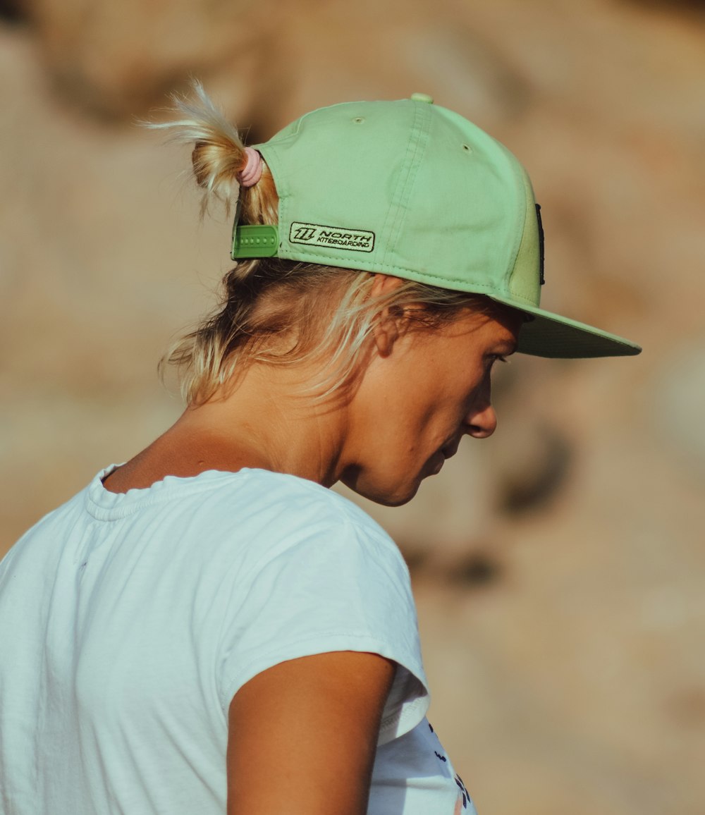 tilt-shift photography of woman with green fitted cap at daytime