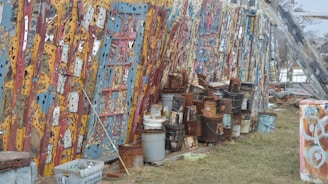 Buckets of weather-resistant paint lined up outdoors under sunlight.
