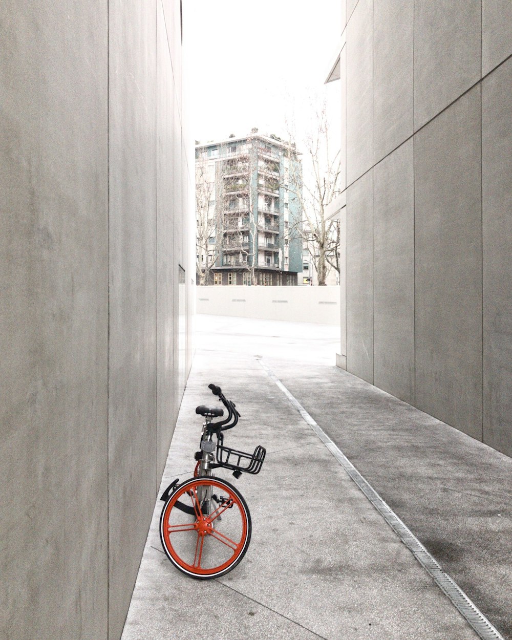 Vélo noir et orange entre les murs de béton