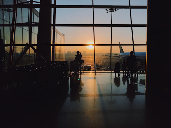 A quiet airport terminal bathed in soft morning light, with travelers pausing between journeys.