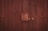 A wooden door with vertical planks and a large central latch bolted securely. The texture of the wood is rough, with visible grain and a dark brown finish.