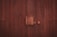 A wooden door with vertical planks and a large central latch bolted securely. The texture of the wood is rough, with visible grain and a dark brown finish.