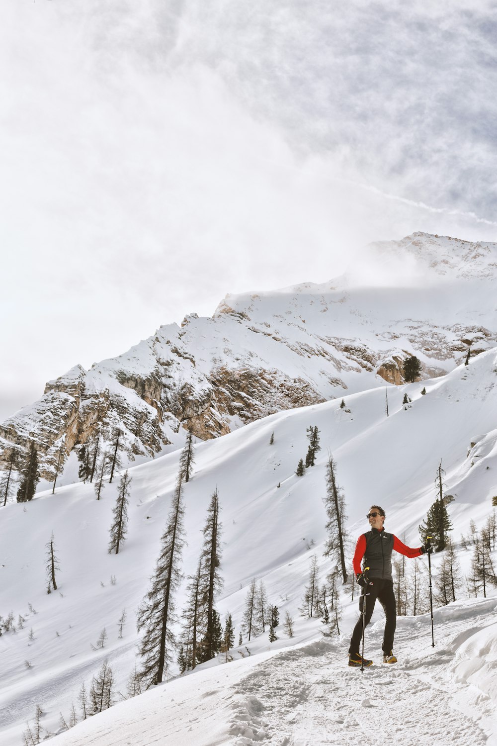 person skiing on snow capped filled with trees at daytime