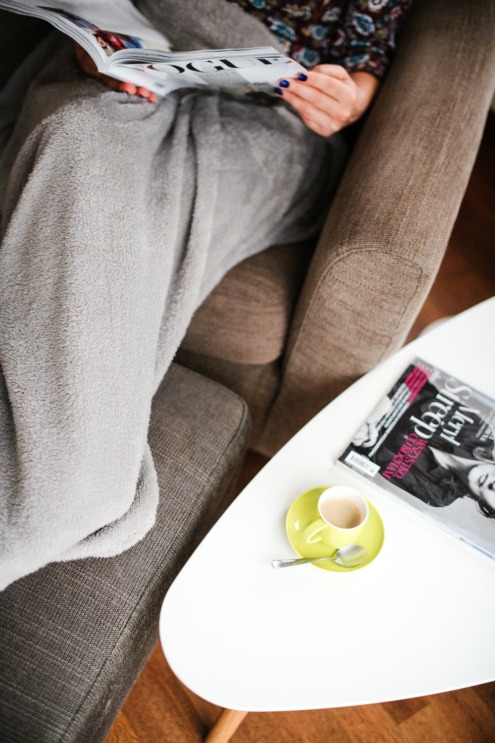 채워진 녹색 세라믹 커피 컵 옆에 잡지를 읽는 여자