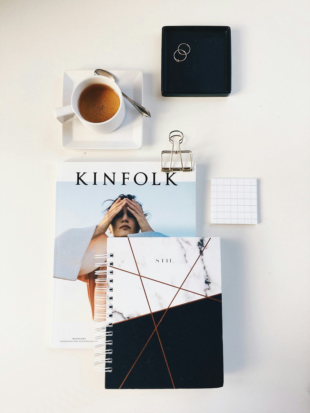 flat lay photography of cup, rings, and notebook
