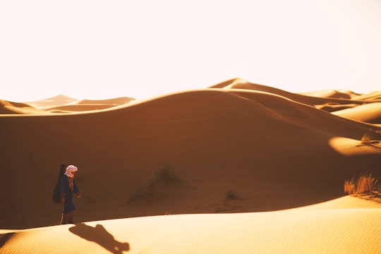 man walking on desert at daytime in Erg Chebbi Morocco