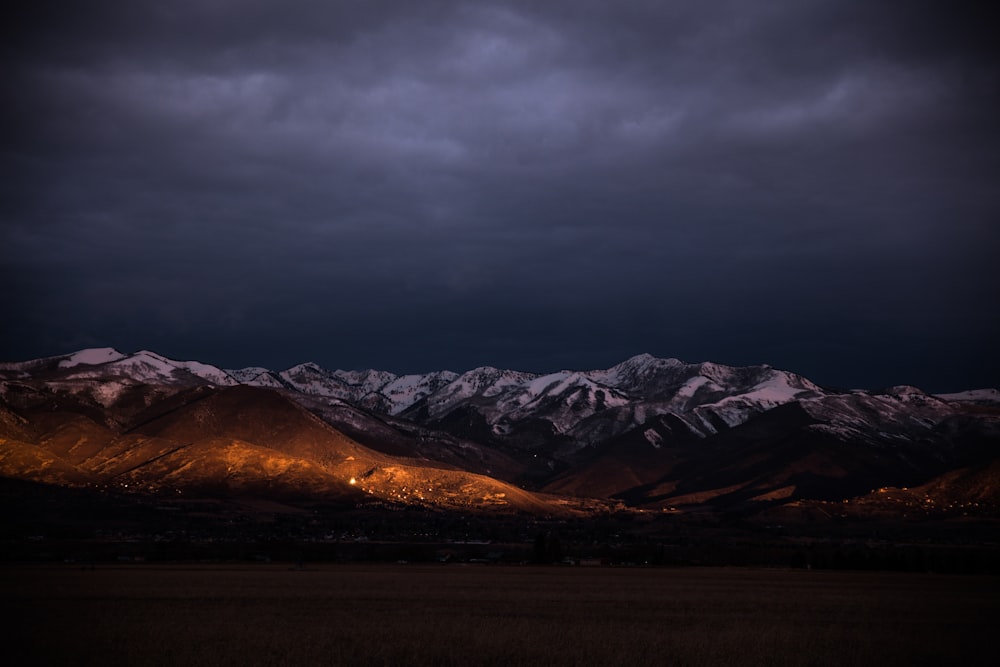 brown mountain under gray clouds during golden hour