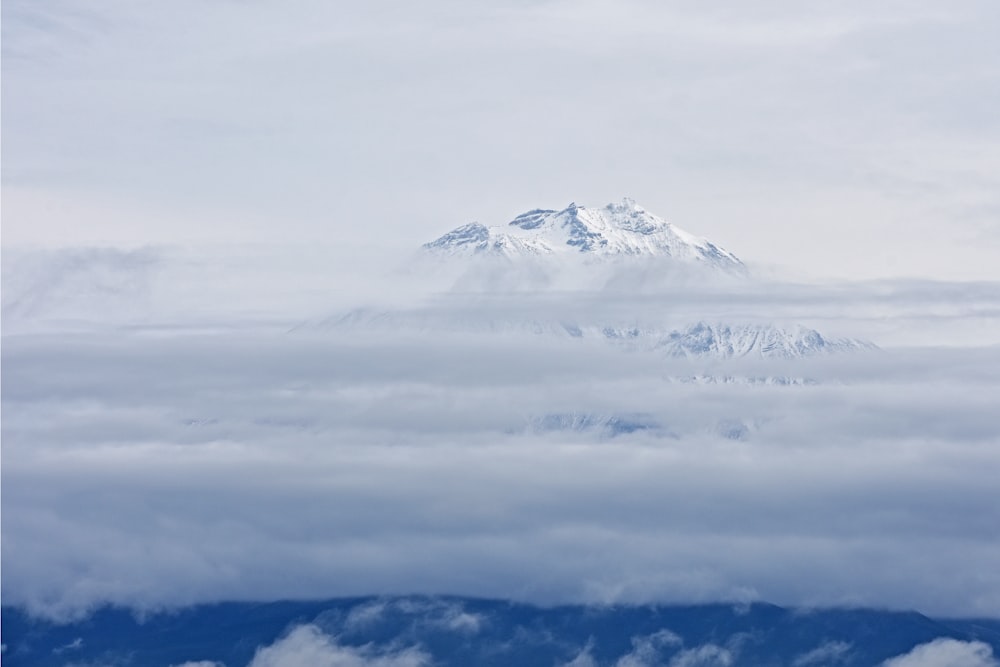 Montaña nevada rodeada de nubes durante el día