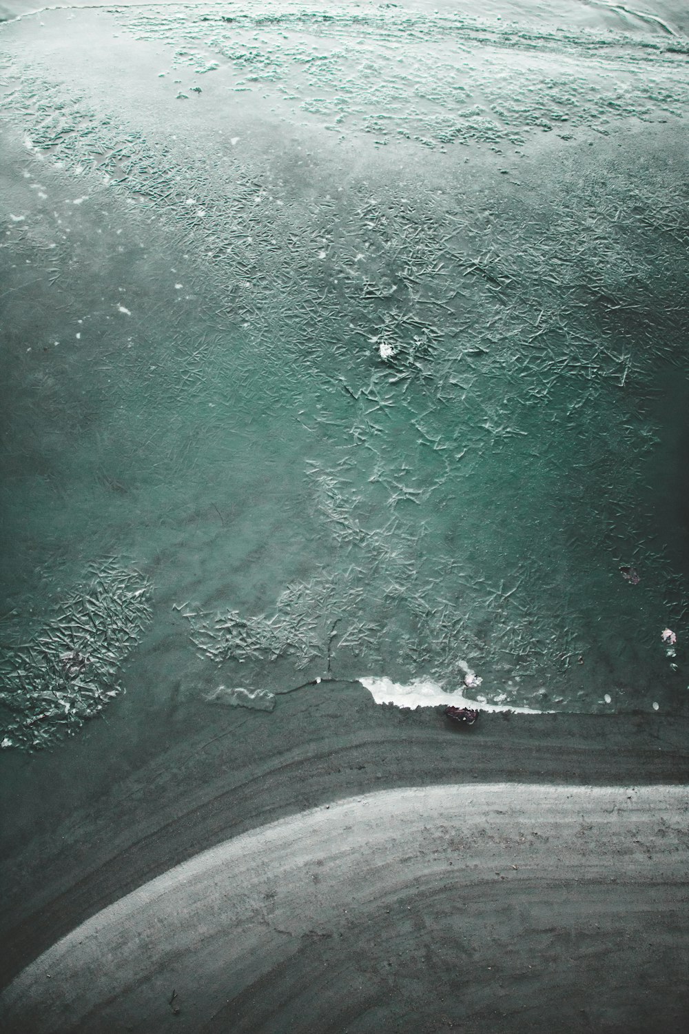 bird's eye view photo of grey sand near body of water