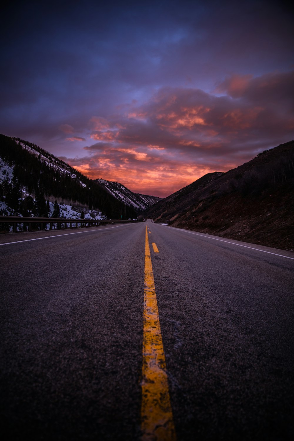 estrada de asfalto cinza entre montanhas marrons sob céu nublado durante o dia