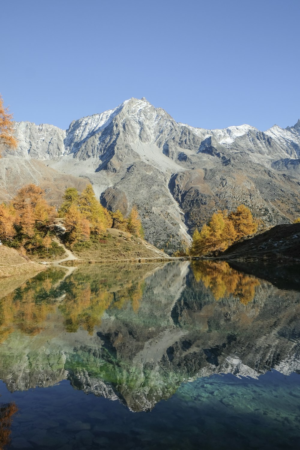 montagna grigia accanto allo specchio d'acqua