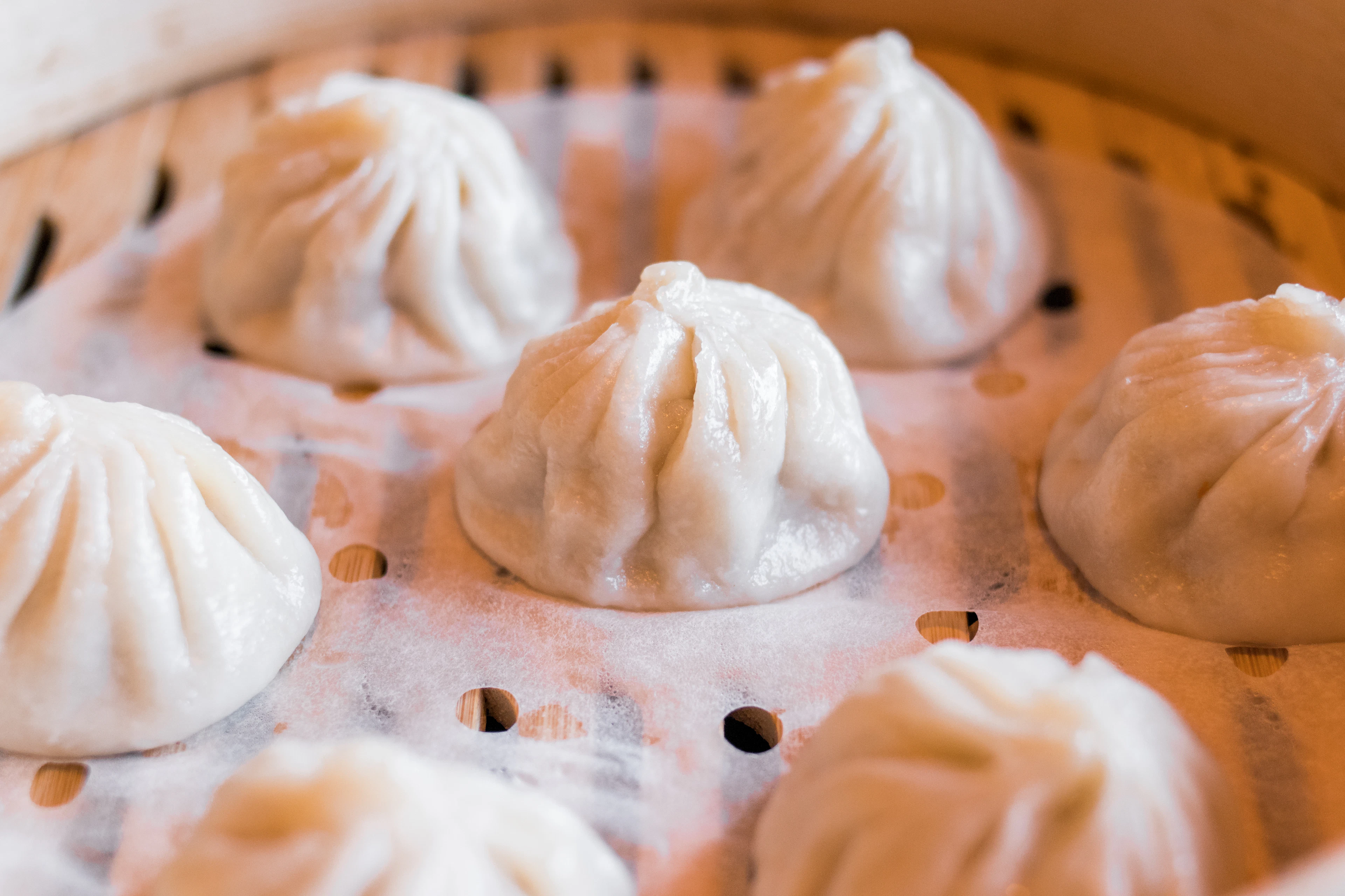 Soup dumplings in a bamboo steamer, in bright warm light
