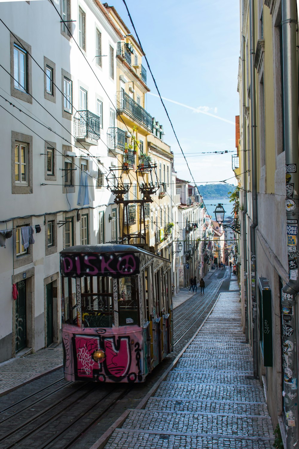 pink tram train beside concrete buildings at daytime