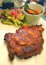 Juicy grilled steak served with fresh salad and rustic potatoes on a ceramic plate.