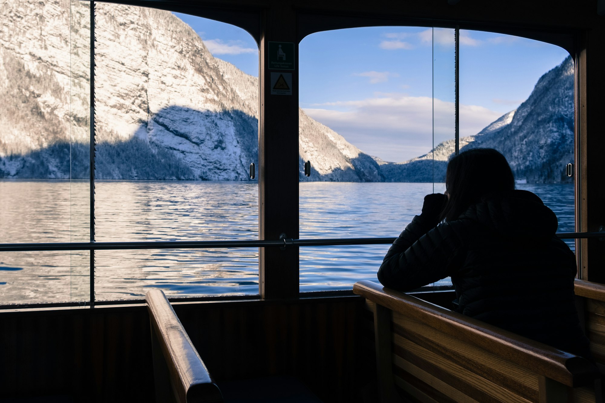 Woman thoughtfully admires a lake view from boat.