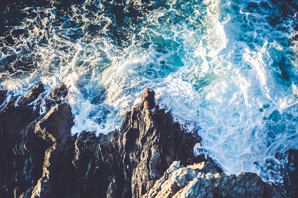 high angle photo of beach wave crushing on rocks