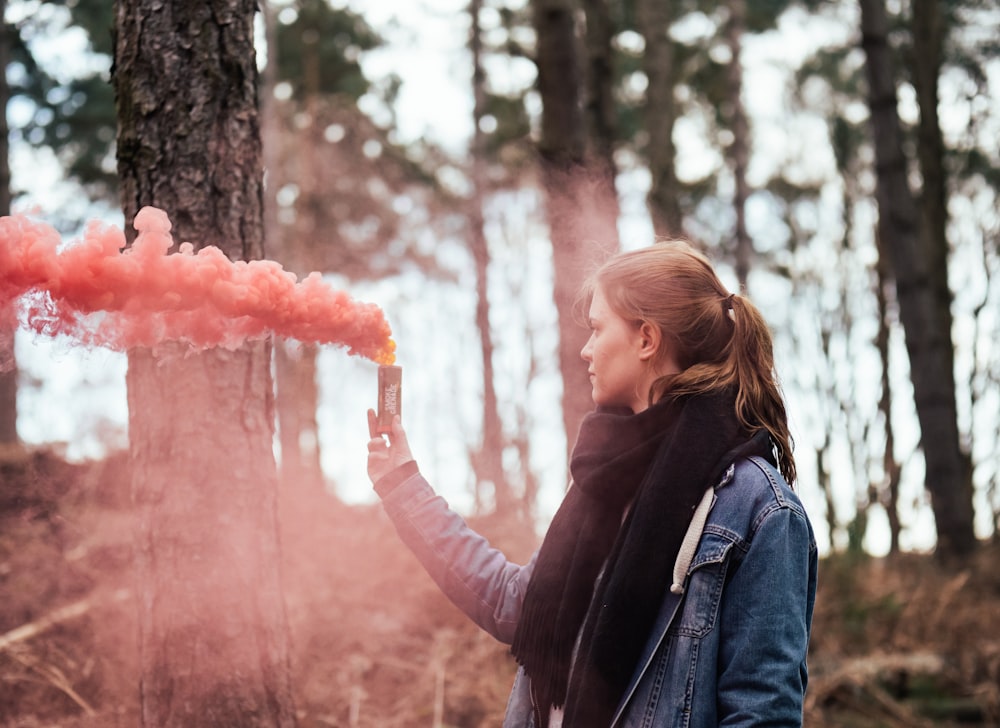 Mujer sosteniendo una botella soplando humo rosa