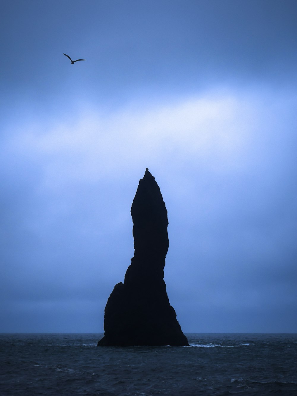 Silhouette einer Felsformation mitten im Meer