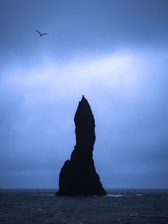 silhouette of rock formation in the middle of sea in Reynisdrangar Iceland