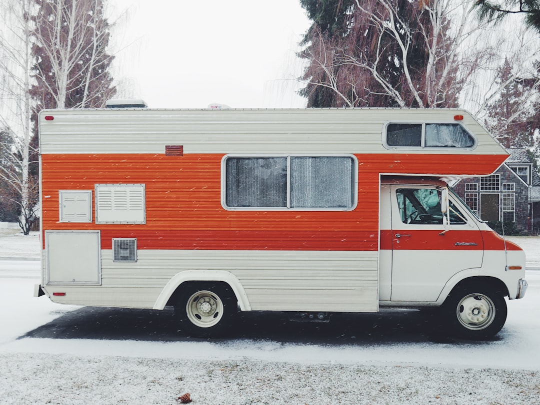 orange and white class-a motorhome surrounded by snow,