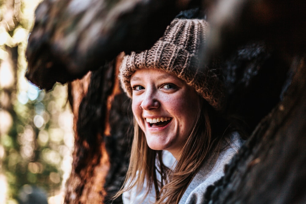 closeup photography of smiling woman beside brown tree