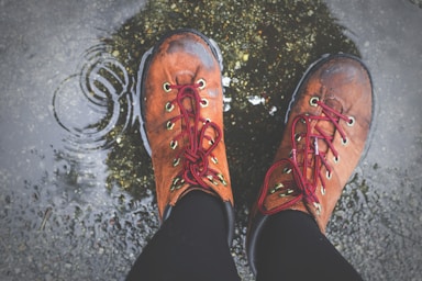 perspective and angle for photo composition,how to photograph rings by rain; person wearing brown lace-up boots standing on wet ground