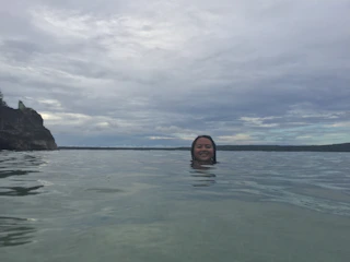 Portrait of Calvin smiling, with scuba gear and ocean backdrop.