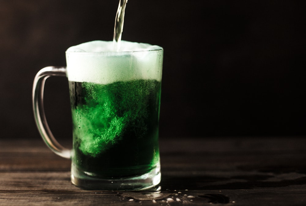 taza de vidrio transparente llena de líquido verde