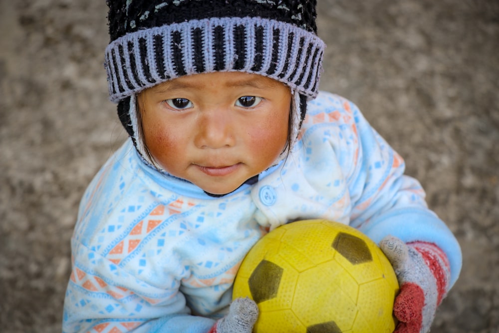 baby in blue and white shirt holding a ball