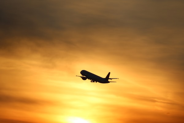 An airplane is taking off with a beautiful sunset in the background (Photo by Daniel De Ciantis / Unsplash)