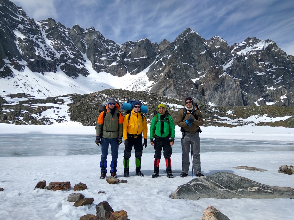 Cuatro hombres tomando una foto grupal frente a la montaña nevada