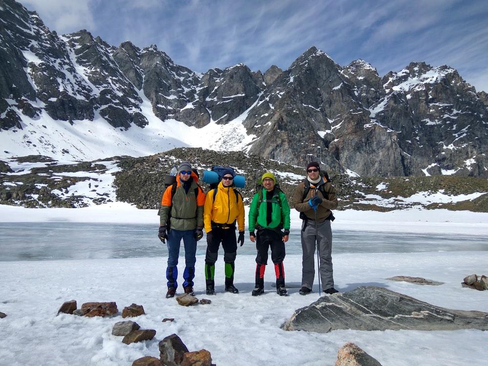 four men taking group photo in front of snow mountain