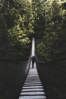 photo of man walking of foot bridge