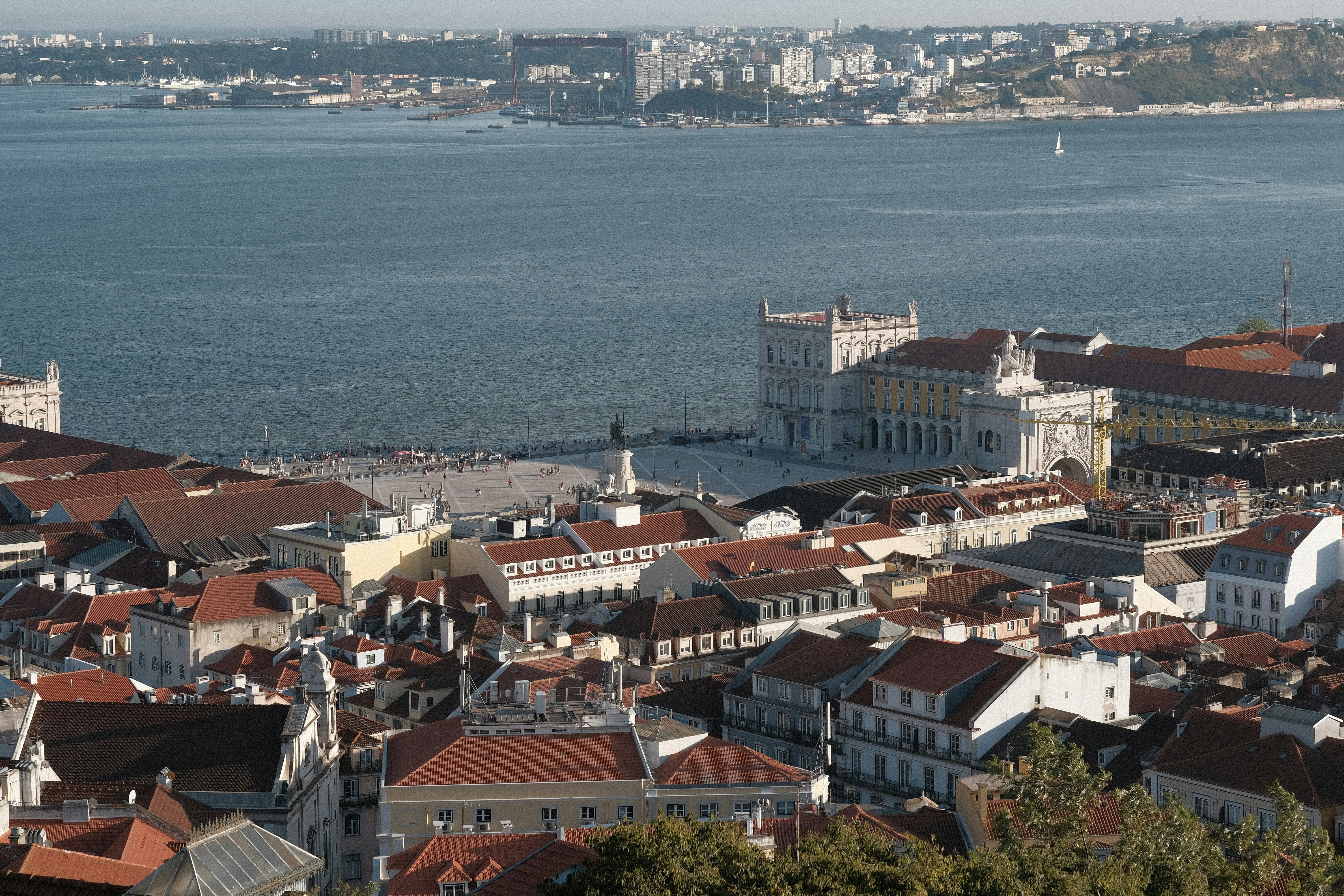 Lisbon hilltop viewpoint at sunset, terracotta rooftops and the Tagus River stretching into the golden horizon