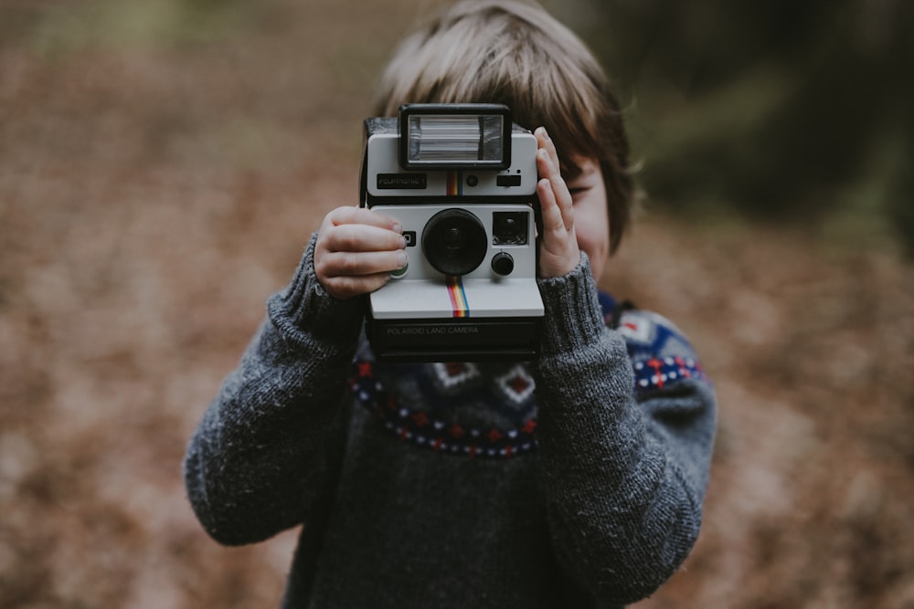 boy using white and black instant camera
