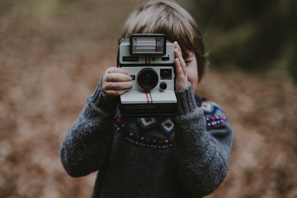 garçon utilisant un appareil photo instantané blanc et noir