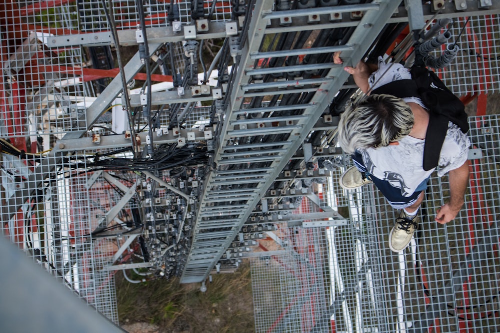 man carrying backpack while standing on high structure looking down