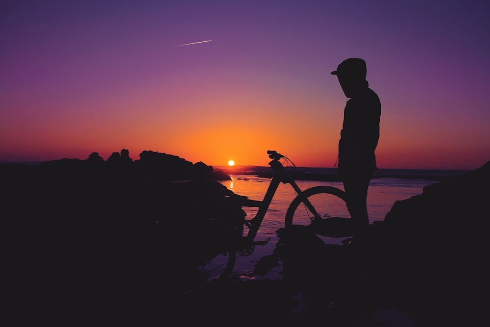 silhouette of person standing near bicycle