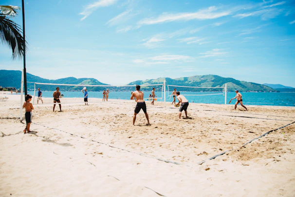 A lively beach scene with friends playing volleyball on Ipanema sand under a bright blue sky
