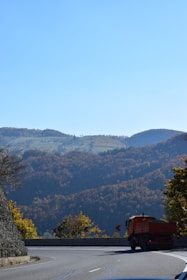 A scenic view of a truck driving through a forested area in autumn.