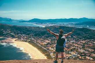 man standing front of seashore and houses
