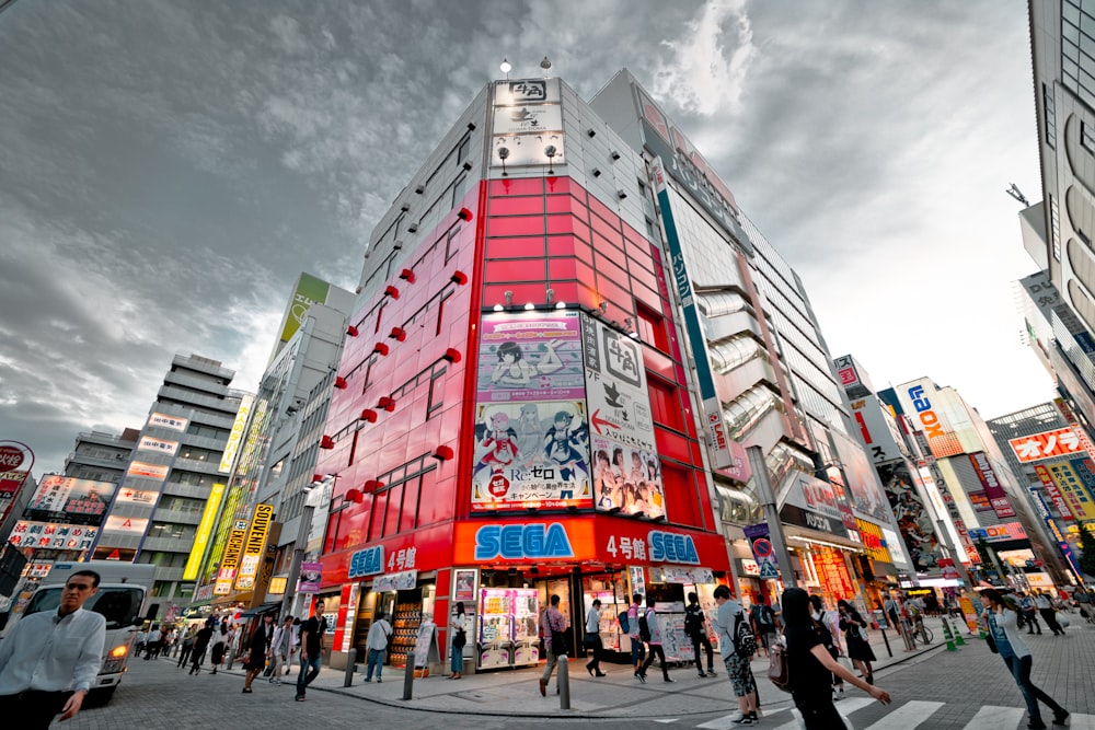 people walking in front of red high-rise building under gray clouds