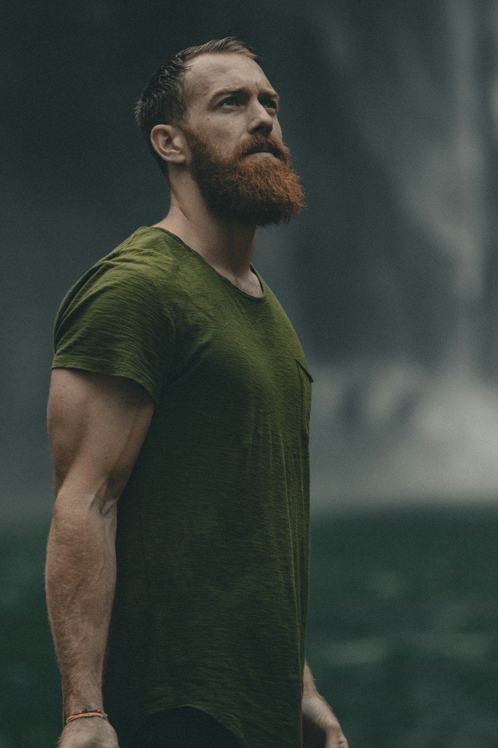 uomo che indossa una t-shirt girocollo verde che guarda verso l'alto