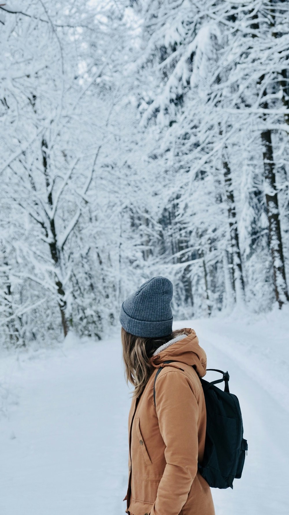 Fotografia de foco raso da mulher em pé no campo de neve olhando suas costasj