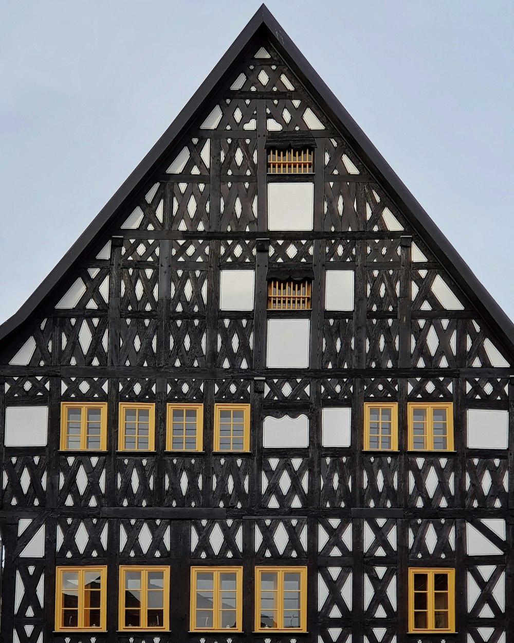 Edifício de madeira preto, bege e branco com várias janelas