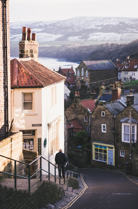 man standing near white painted house in Robin Hood's Bay United Kingdom