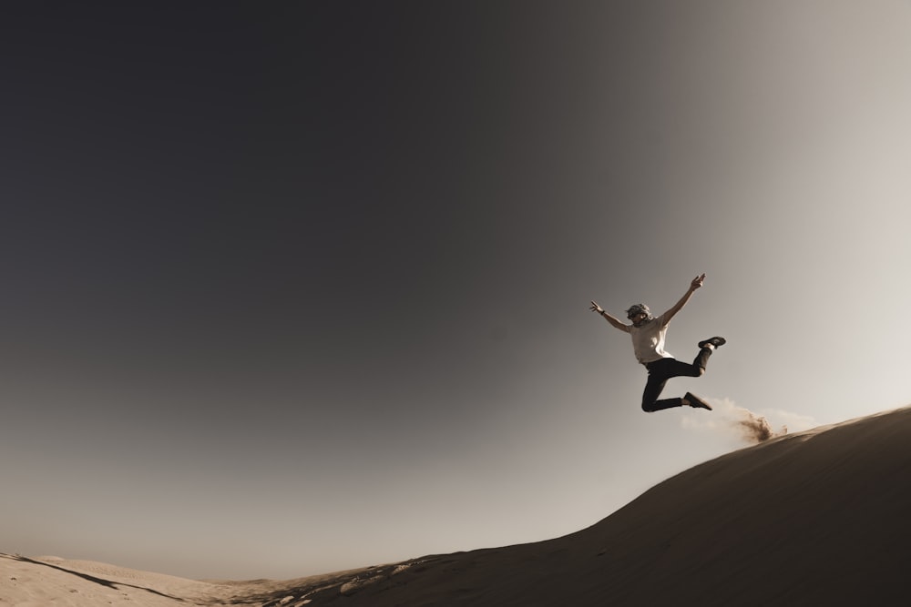 personne sautant d’une dune de sable pendant la journée